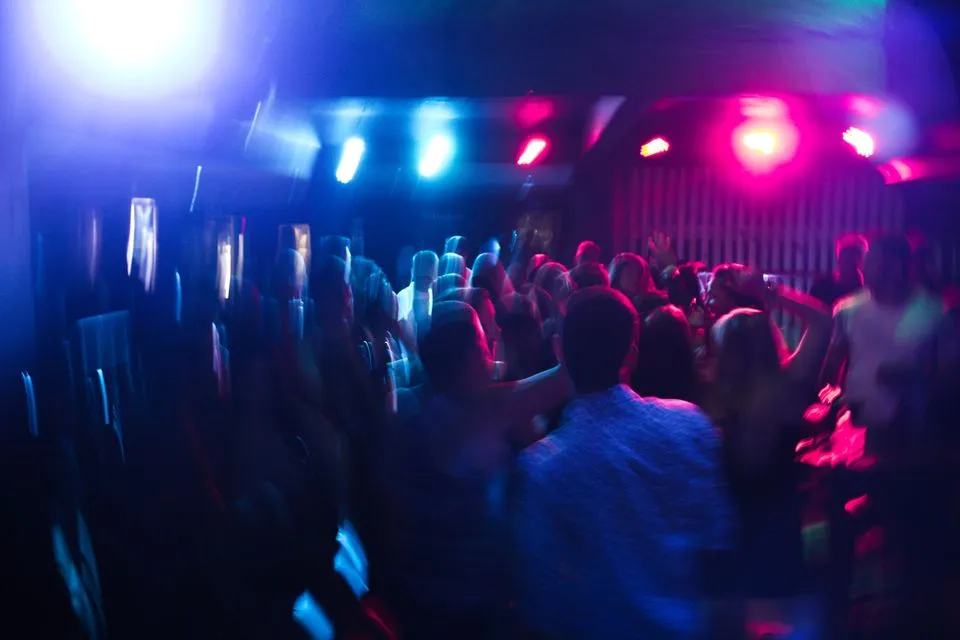 Multidão dançando em nightclub com luzes coloridas na quarta edição do Encontro das Rodas de Samba