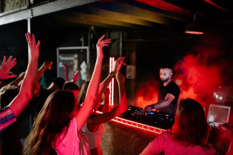 Pessoas dançando em pista de nightclub com luzes coloridas na quinta edição do Encontro das Rodas de Samba